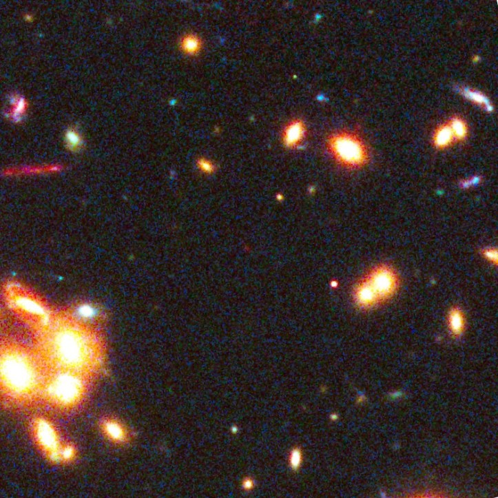 Mica pată roșie din centrul imaginii este obiectul în cauză. Foto: Undeva în această imagine se află una dintre cele mai îndepărtate galaxii din Univers. Foto: NASA, ESA, W. Zheng (JHU), M. Postman (STScI), and the CLASH Team